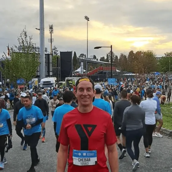Maxime wears a YMCA t-shirt and race bib near the finish line of the BMO Vancouver Marathon
