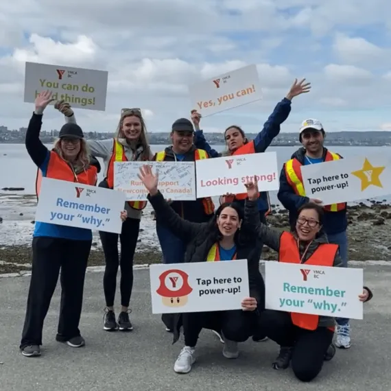 Several YMCA volunteers hold signs with encouraging messages for Vancouver Marathon runners