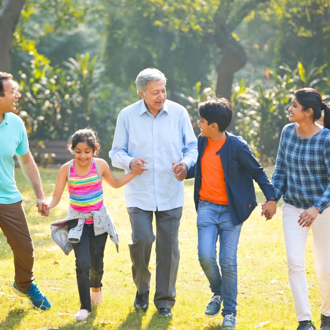 Five members of a three-generation family walk together holding hands, with the patriarch in the middle